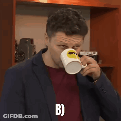 A Man In A Suit Is Holding A Coffee Mug With A Smiley Face On It And The Letter B On The Bottom GIF
