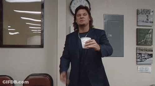 A Man In A Suit Is Holding A Cup In Front Of A Clock That Shows The Time As 8:15 GIF