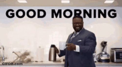 A Man In A Suit Is Holding A Cup Of Coffee In Front Of A Sign That Says Good Morning . GIF