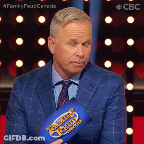 A Man In A Suit Is Holding A Family Feud Canada Sign GIF