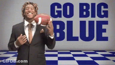 A Man In A Suit Is Holding A Football In Front Of The Words Go Big Blue GIF