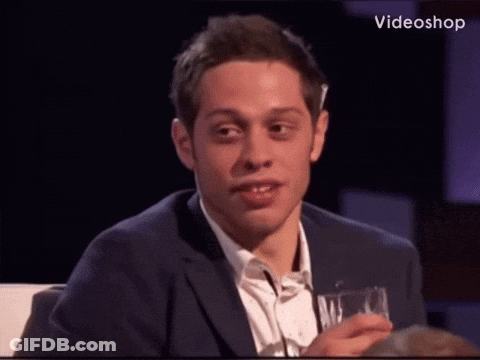 A Man In A Suit Is Holding A Glass And Making A Funny Face GIF