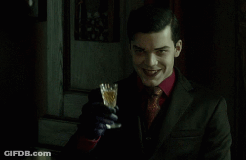 A Man In A Suit Is Holding A Glass In His Hand GIF