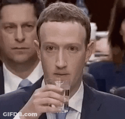 A Man In A Suit Is Holding A Glass Of Water In His Hand . GIF