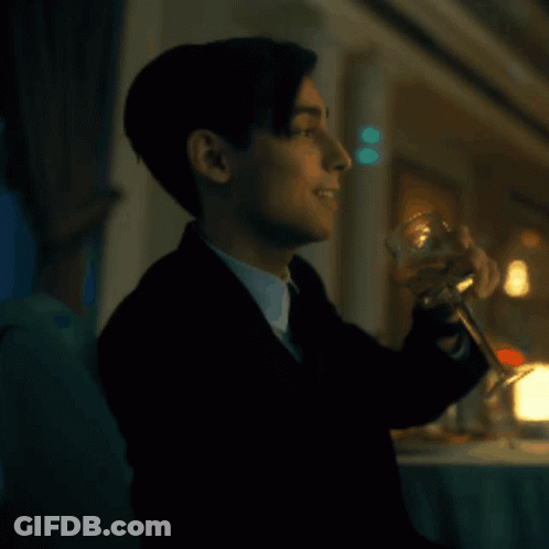 A Man In A Suit Is Holding A Glass Of Wine GIF