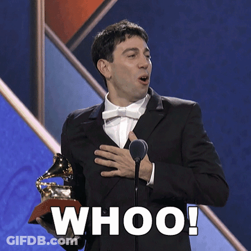 A Man In A Suit Is Holding A Grammy Trophy And Says Whoo GIF