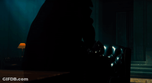 A Man In A Suit Is Holding A Hourglass In His Hands GIF