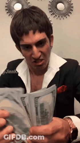 A Man In A Suit Is Holding A Large Stack Of Money GIF
