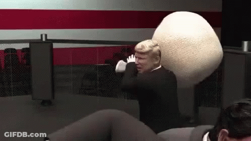A Man In A Suit Is Holding A Large White Ball In His Hands . GIF