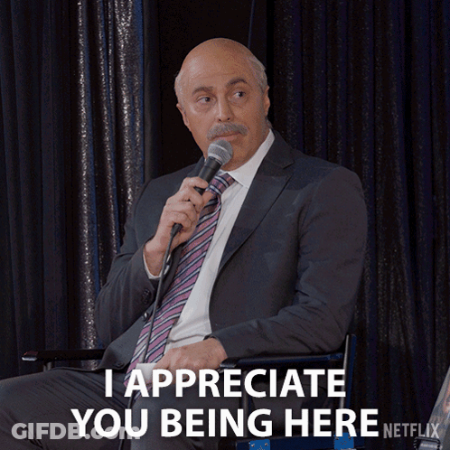 A Man In A Suit Is Holding A Microphone And Says I Appreciate You Being Here GIF