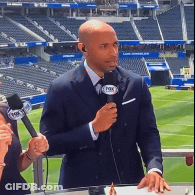 A Man In A Suit Is Holding A Microphone With The Fox Logo On It GIF