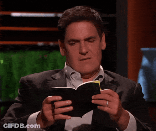 A Man In A Suit Is Holding A Pen And A Piece Of Paper GIF