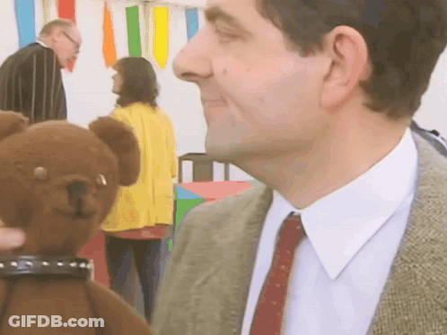 A Man In A Suit Is Holding A Teddy Bear GIF