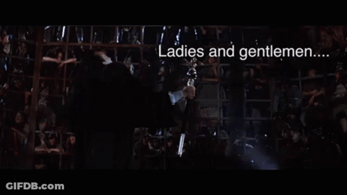 A Man In A Suit Is Holding A Trophy In His Hand And Saying `` Dyin ' Time 'S Here '' . GIF