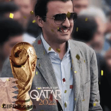 A Man In A Suit Is Holding A Trophy That Says Qatar 2022 GIF