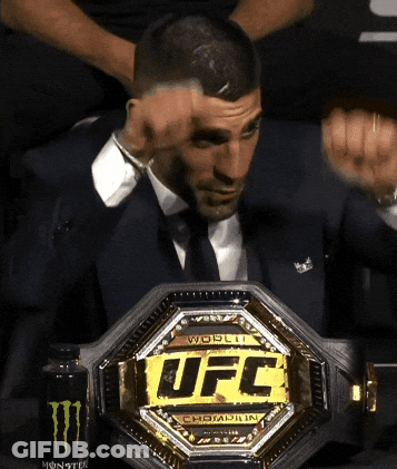 A Man In A Suit Is Holding A Ufc Belt GIF