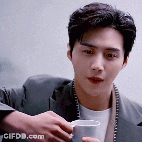 A Man In A Suit Is Holding A White Cup GIF
