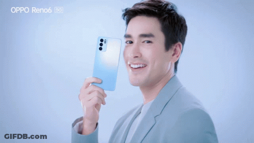 A Man In A Suit Is Holding An Oppo Reno6 GIF