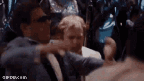A Man In A Suit Is Holding Another Man 'S Arm In A Crowd Of People . GIF