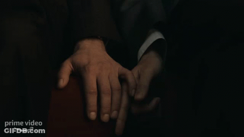 A Man In A Suit Is Holding Another Man 'S Hand In A Dark Room With A Prime Video Logo In The Corner GIF