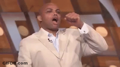 A Man In A Suit Is Holding His Fist Up In The Air . GIF