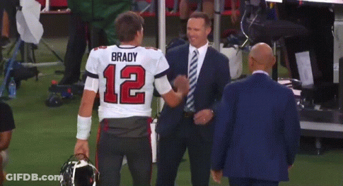 A Man In A Suit Is Hugging A Man In A Brady Jersey GIF