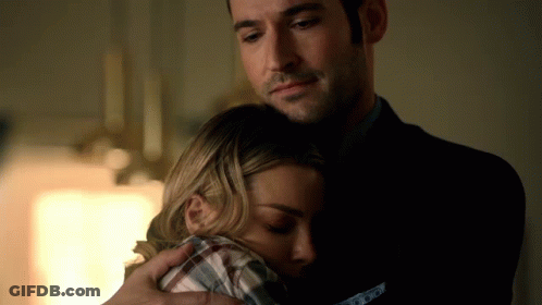 A Man In A Suit Is Hugging A Woman In A Plaid Shirt In A Dark Room GIF