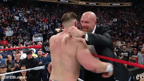 A Man In A Suit Is Hugging Another Man In A Ring GIF