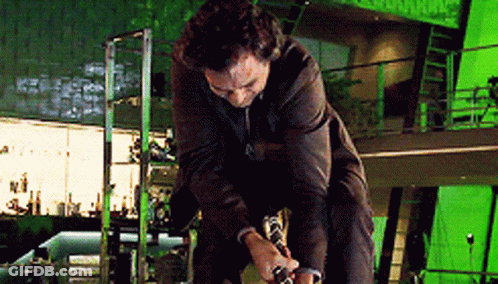 A Man In A Suit Is Kneeling Down In Front Of A Green Screen . GIF