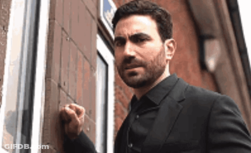 A Man In A Suit Is Knocking On A Door With His Fist . GIF