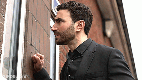 A Man In A Suit Is Knocking On A Window GIF