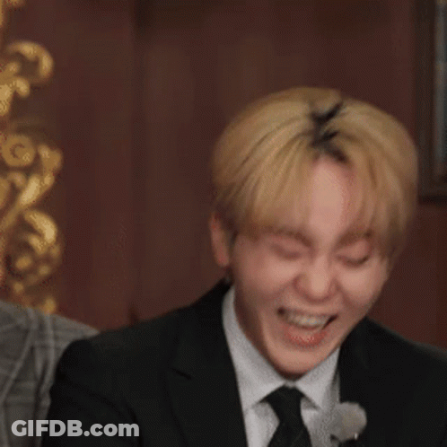 A Man In A Suit Is Laughing And Holding A Piece Of Paper GIF