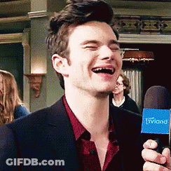 A Man In A Suit Is Laughing While Holding A Microphone That Says Tvland GIF