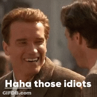 A Man In A Suit Is Laughing While Talking To Another Man In A Suit . GIF