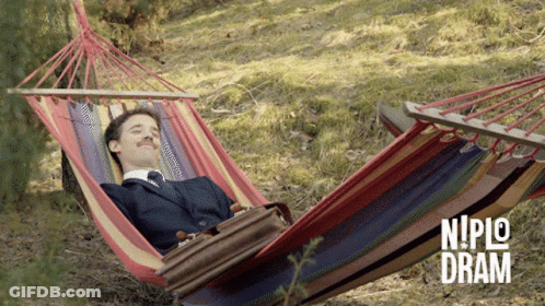 A Man In A Suit Is Laying In A Hammock With Niplo Dram Written On The Bottom Right GIF