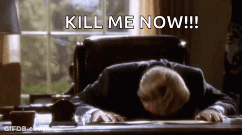 A Man In A Suit Is Laying On A Desk With His Head On The Desk And The Words `` Kill Me Now '' Written Above Him . GIF