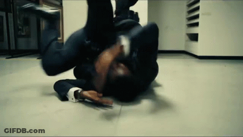 A Man In A Suit Is Laying On The Floor In A Room . GIF