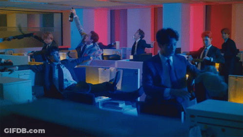 A Man In A Suit Is Laying On The Floor In An Office GIF