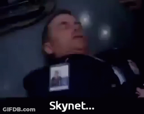 A Man In A Suit Is Laying On The Floor With The Words The Virus Has Infected Skynet Below Him GIF