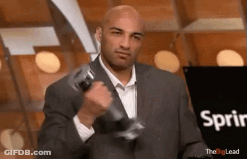 A Man In A Suit Is Lifting A Dumbbell In Front Of A Sign That Says Sprint . GIF