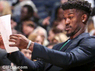 A Man In A Suit Is Looking At A Piece Of Paper . GIF