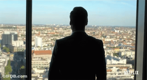 A Man In A Suit Is Looking Out Of A Window With Netflix Written On The Bottom GIF