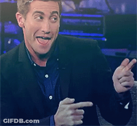 A Man In A Suit Is Making A Face And Pointing At Something GIF