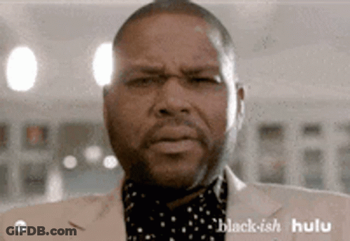 A Man In A Suit Is Making A Funny Face . GIF
