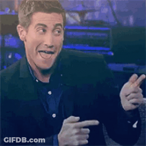A Man In A Suit Is Making A Funny Face While Pointing At Something . GIF