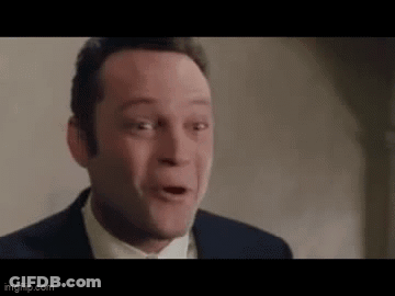 A Man In A Suit Is Making A Funny Face . GIF