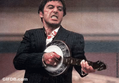 A Man In A Suit Is Playing A Banjo With Blood On His Shirt . GIF