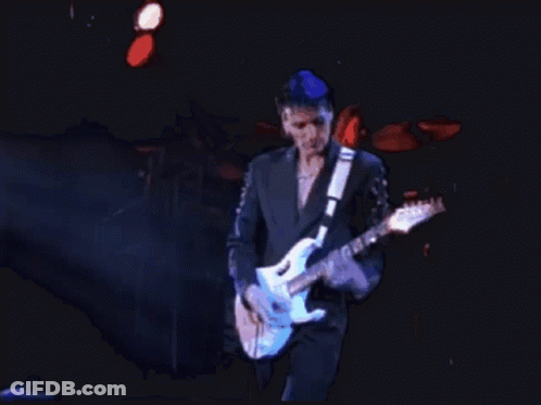 A Man In A Suit Is Playing A Blue Guitar GIF