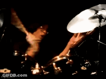 A Man In A Suit Is Playing A Guitar On Stage . GIF