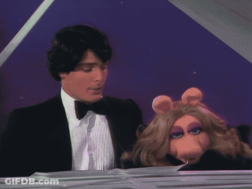 A Man In A Suit Is Playing A Piano Next To Miss Piggy GIF